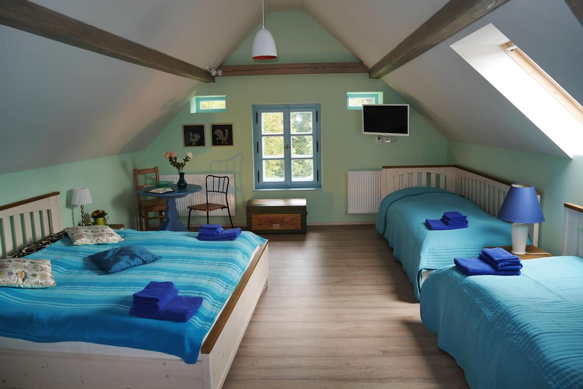 A bedroom with two beds, a desk, a chair, a window, and a television.