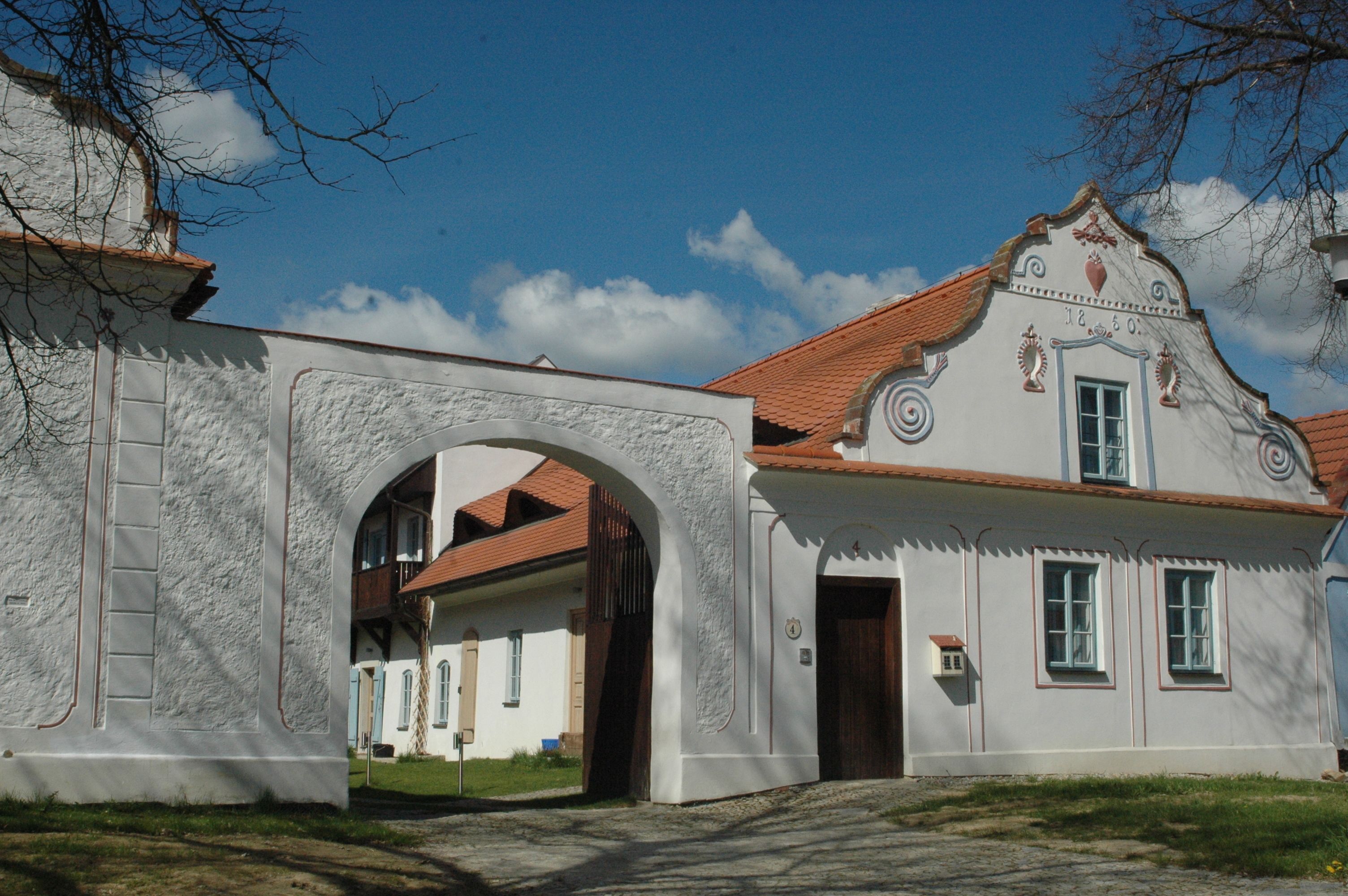 A traditional building with a white facade, a red-tiled roof, and an arched entrance.