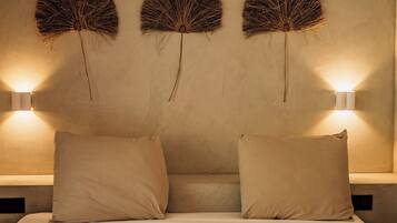 A bed with two pillows and three wall-mounted light fixtures.