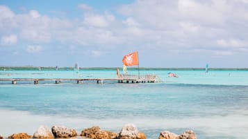 Un muelle que se adentra en aguas turquesas, con una bandera en un asta.