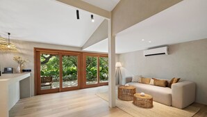 Amplia sala de estar con un sofá moderno, una mesa de centro y un gran ventanal corredero que da a un jardín.