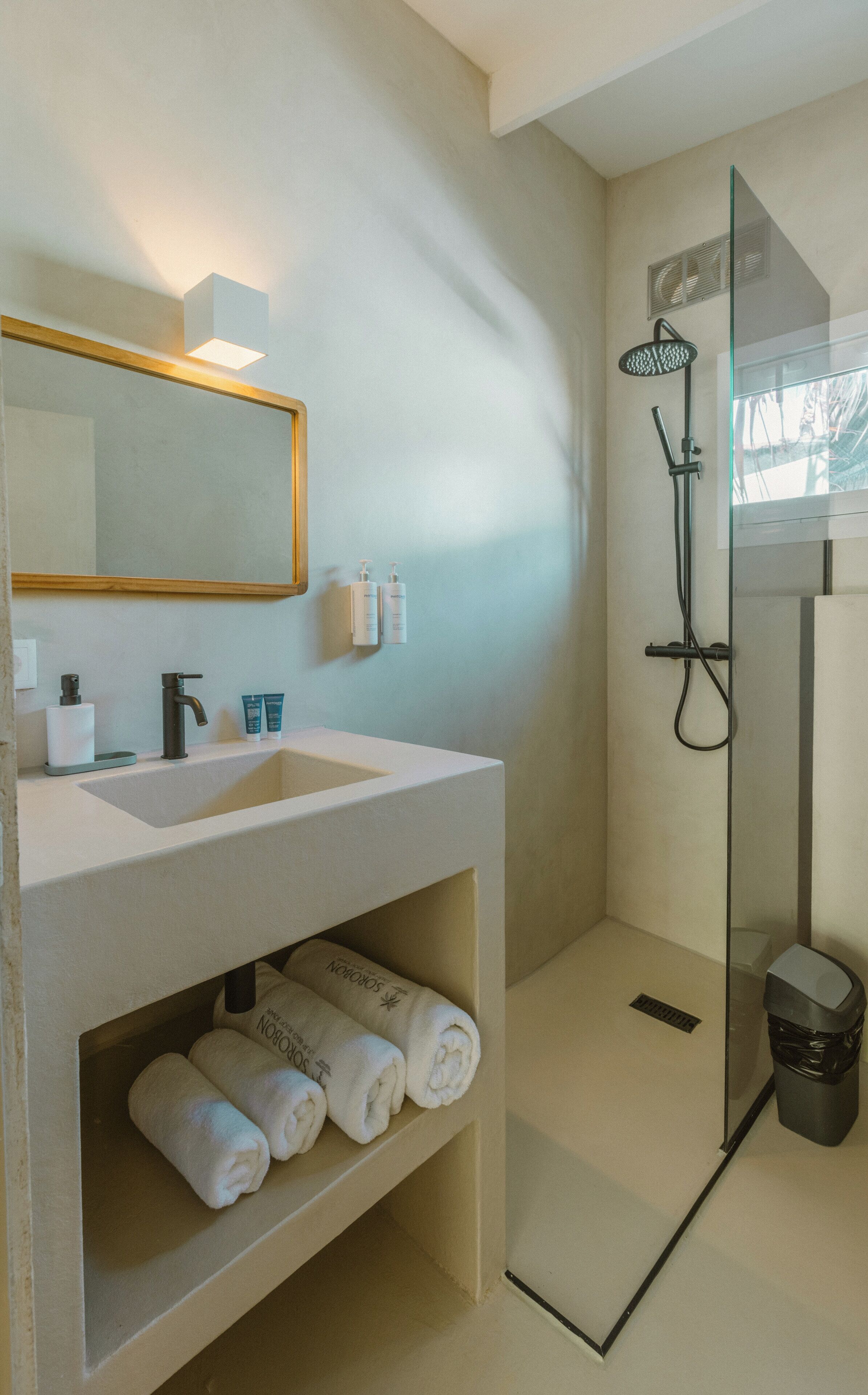 A bathroom with a sink, mirror, towel rack, and shower.