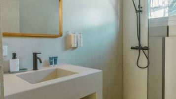A bathroom with a sink, mirror, towel rack, and shower.