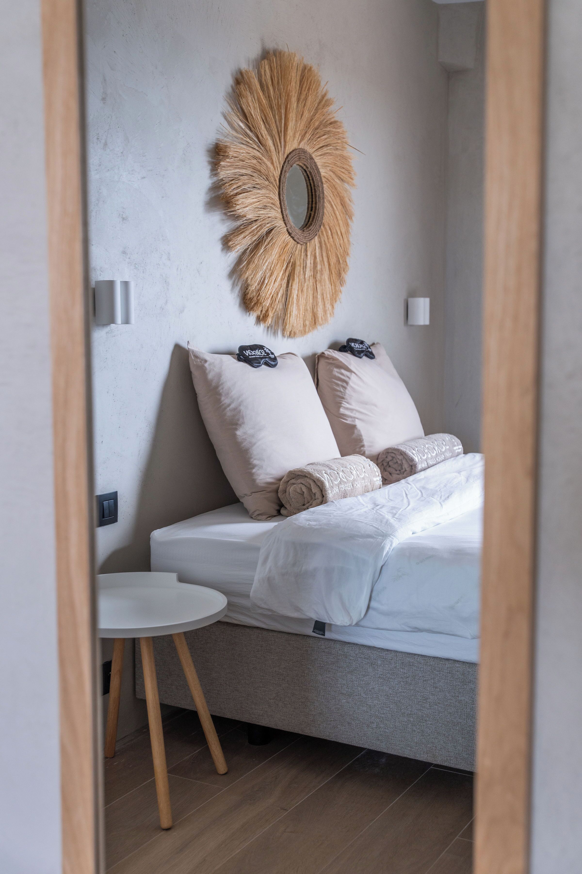 A bedroom with a bed, a round mirror, and a small white table.
