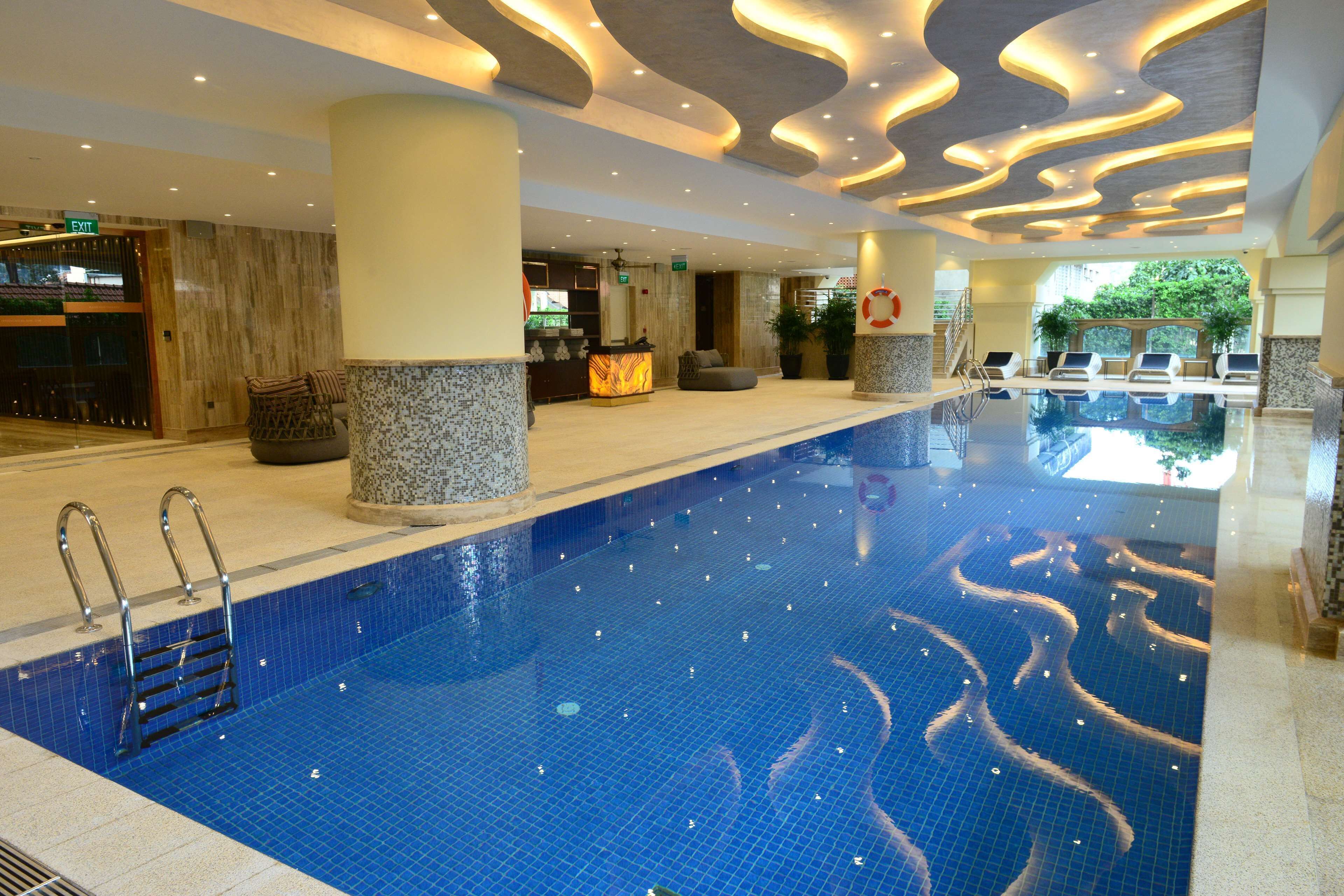 A hotel lobby with a swimming pool, a reception desk, and seating areas.