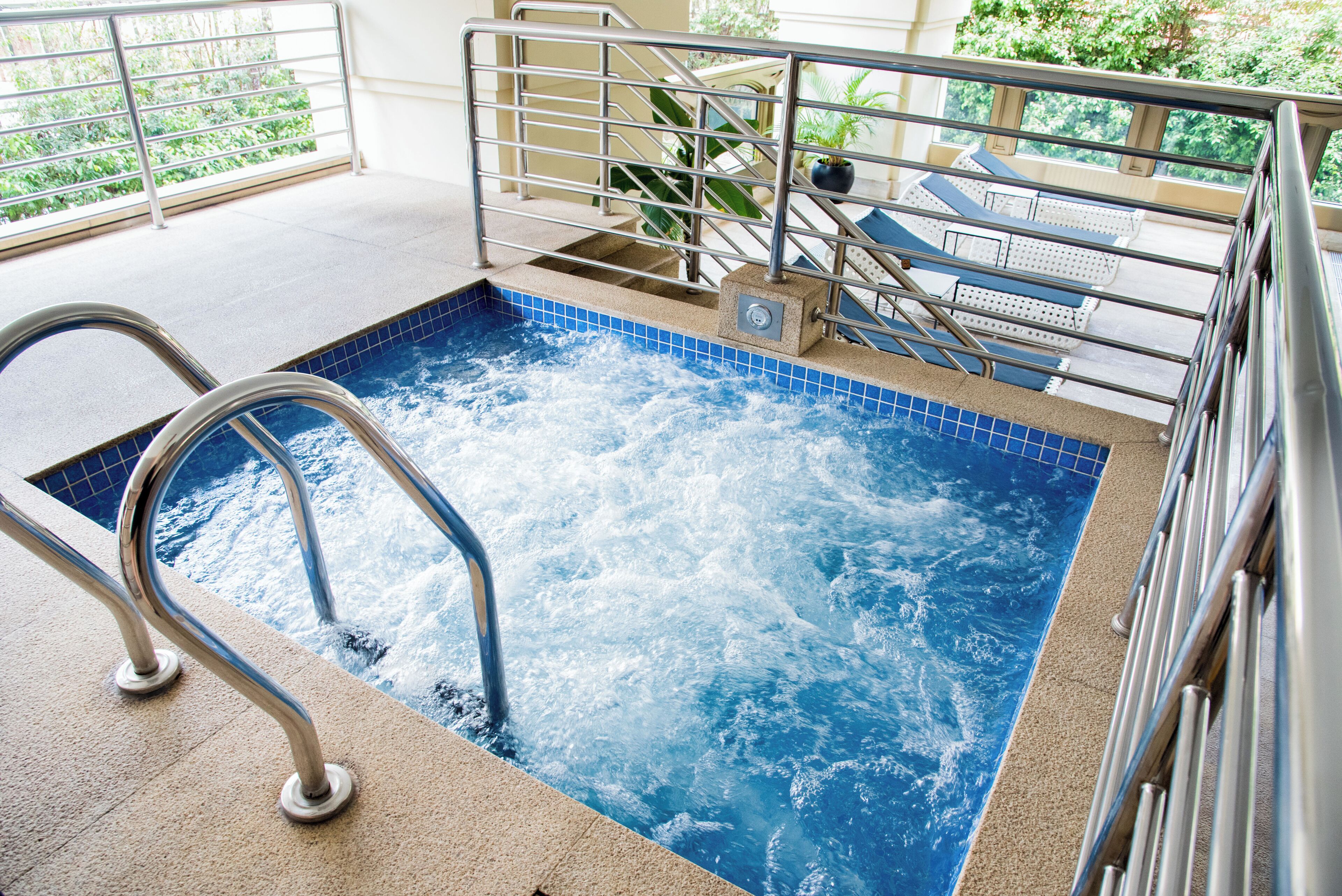 A hot tub with a metal railing and steps leading into it.