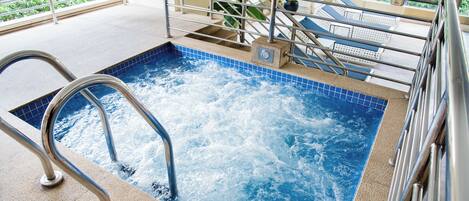 A hot tub with a metal railing and steps leading into it.