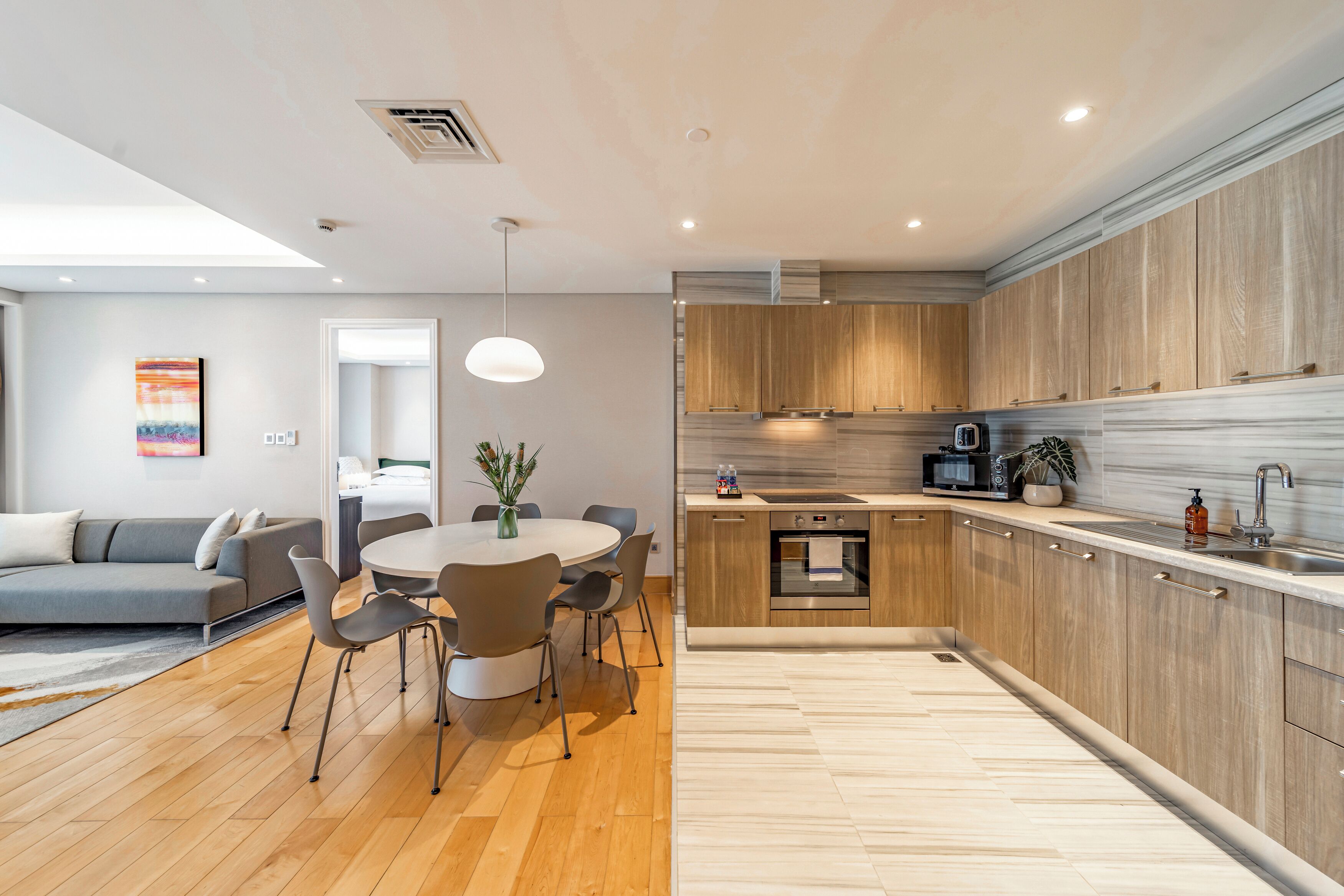 Una cocina moderna con armarios de madera, horno empotrado y pileta de acero inoxidable.
