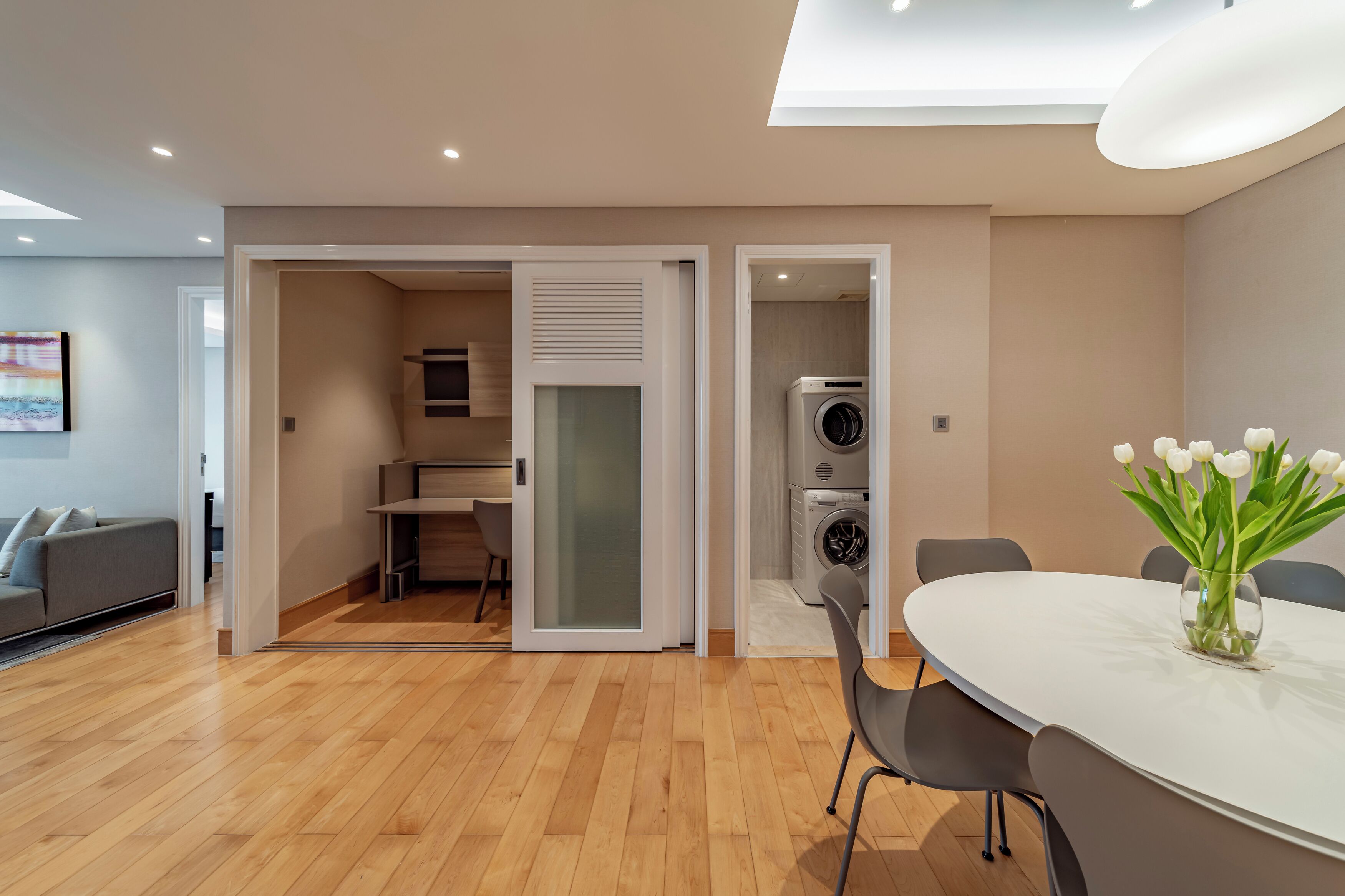 A modern apartment with a dining area, a kitchen, and a laundry room.