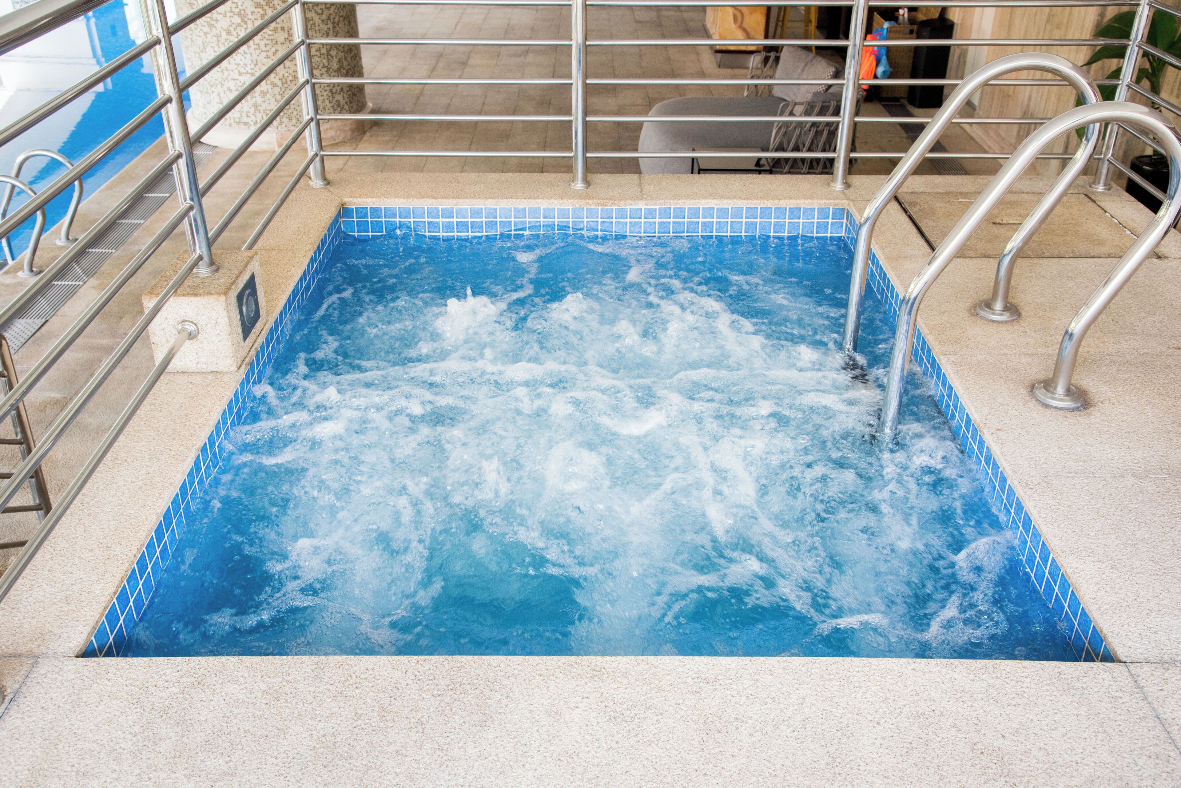 Ein Whirlpool mit Metallgeländern und einer gefliesten Kante.