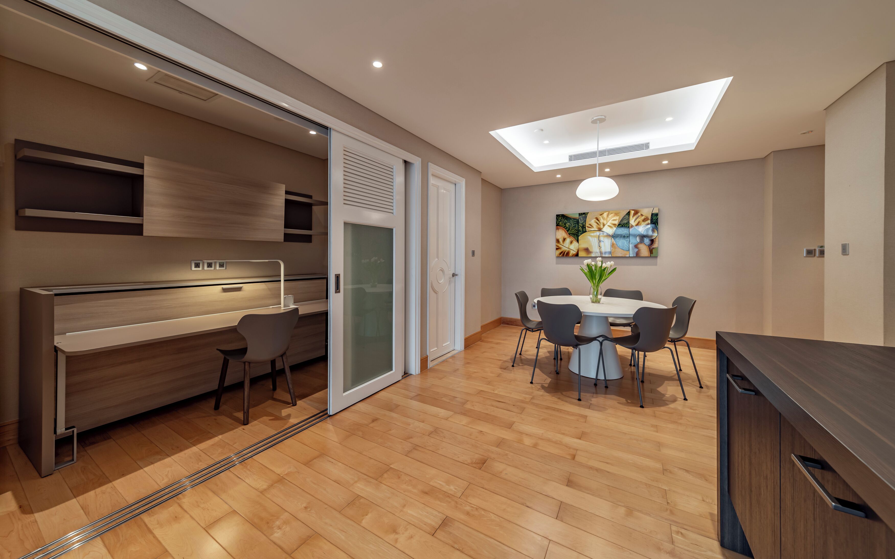 Eine moderne Küche mit Einbauofen, ein Essbereich mit rundem Tisch und Stühlen sowie ein Dachfenster.