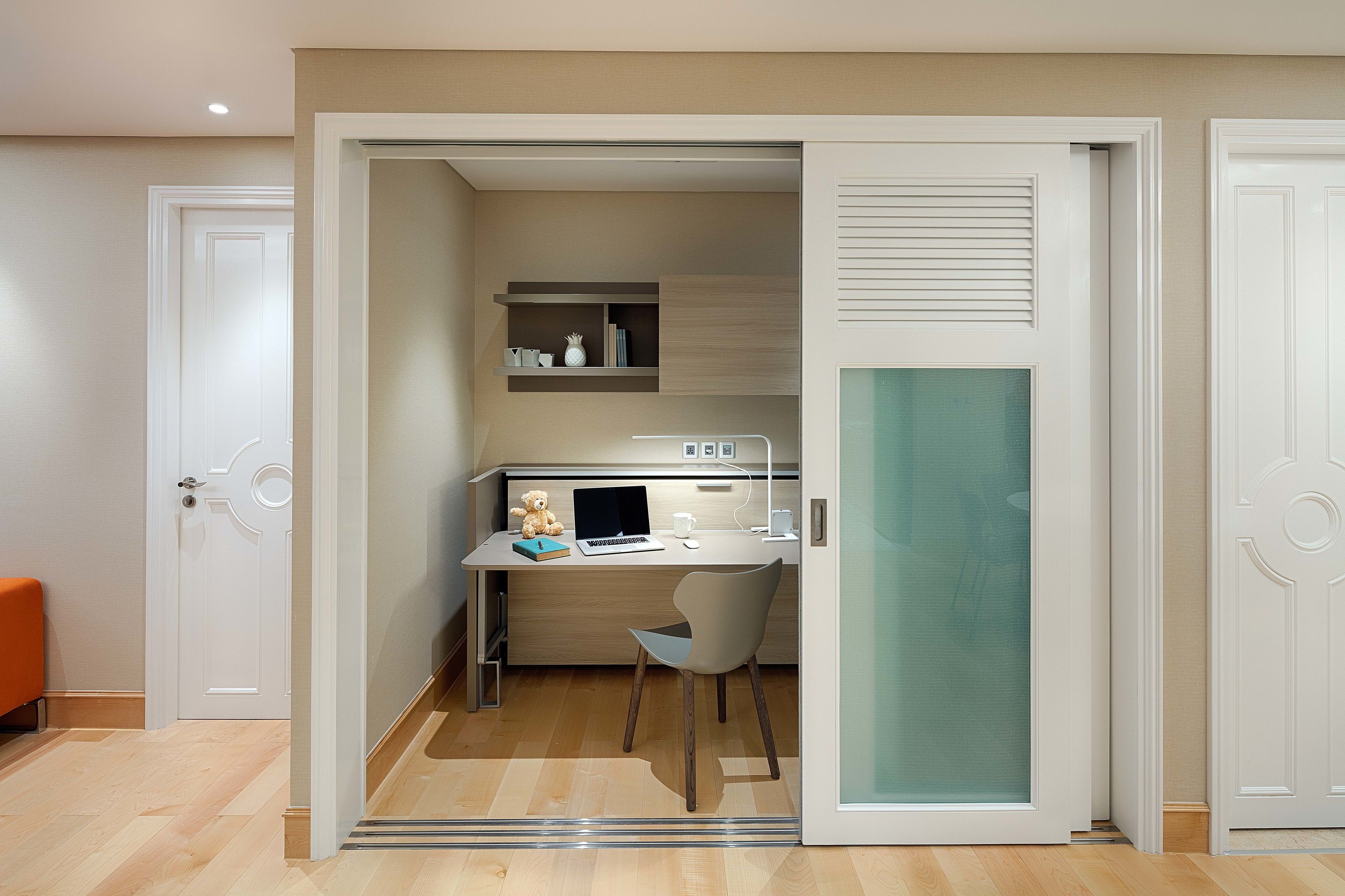 Une pièce de taille modeste comprenant un bureau, une chaise et une petite kitchenette.