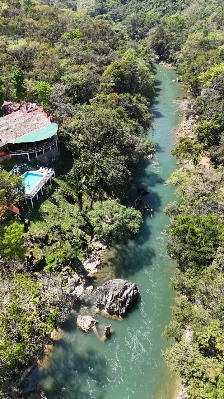 Un río con un edificio a la izquierda, rodeado de abundante vegetación.