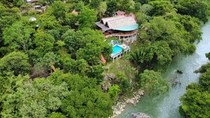 Vista aérea de un resort con piscina, rodeado de exuberante vegetación y un río.