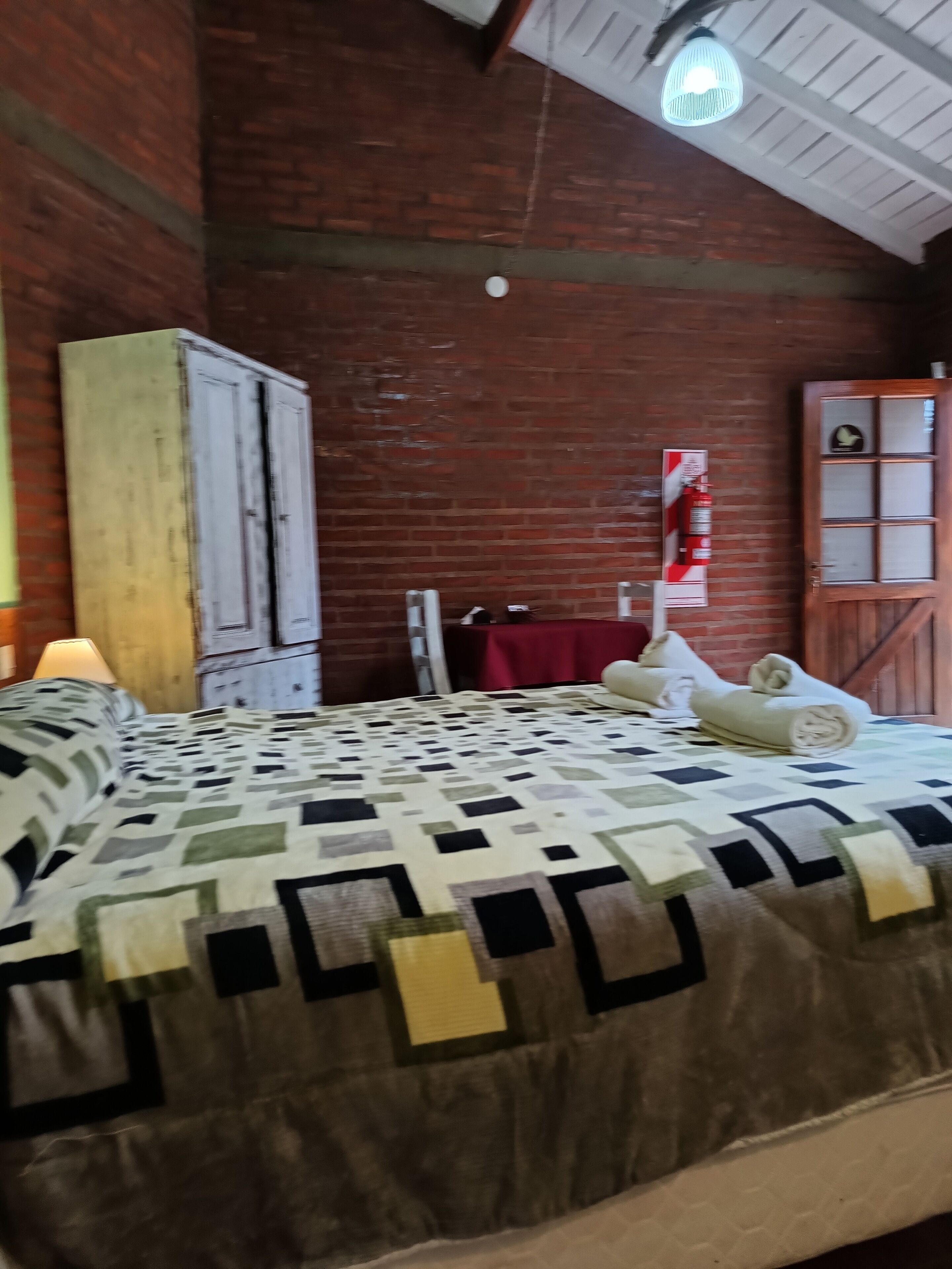 A room with a bed, a wardrobe, a fire extinguisher, and a door.