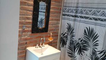 A bathroom with a white sink, a mirror, and a shower curtain with a tropical leaf pattern.