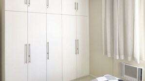 Un dormitorio con un armario blanco grande, un ventilador de techo y un radiador.