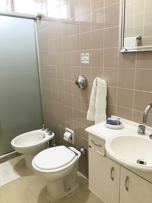 Une salle de bain avec deux toilettes, un bidet, un lavabo et un miroir.