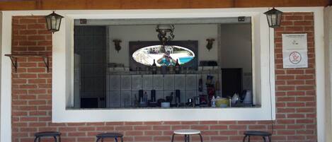 Una zona de bar con un rebozo de azulejos, luces colgantes y taburetes.