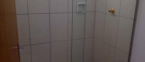 Un baño con cabina de ducha de vidrio, inodoro y una pequeña ventana.