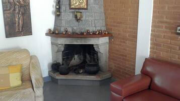 Uma sala de estar com lareira, um sofá e uma poltrona vermelha.