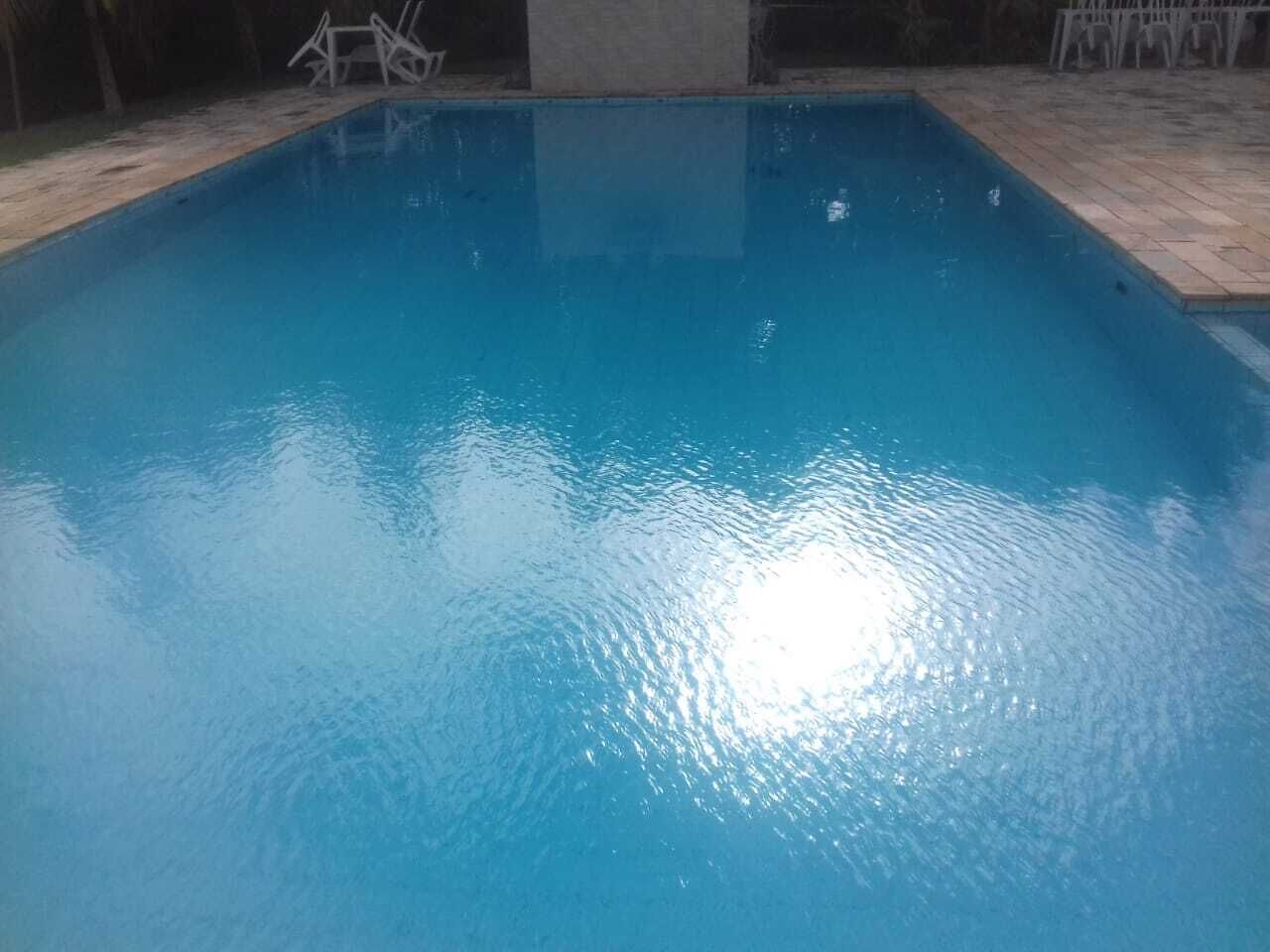 A rectangular swimming pool with clear blue water, surrounded by a tiled deck.