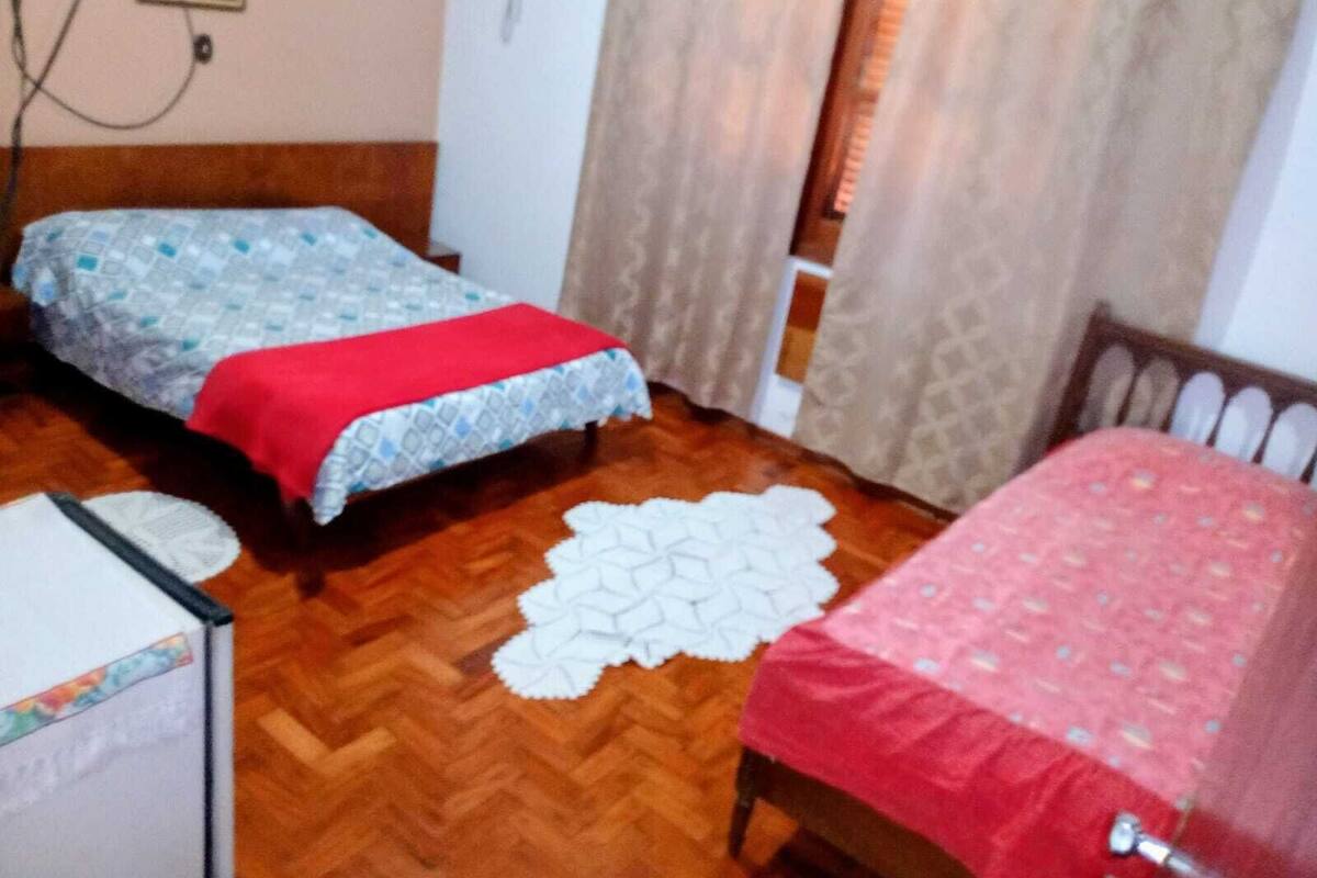 Ein Schlafzimmer mit zwei Betten, Holzboden und einer weißen Spitzendecke.