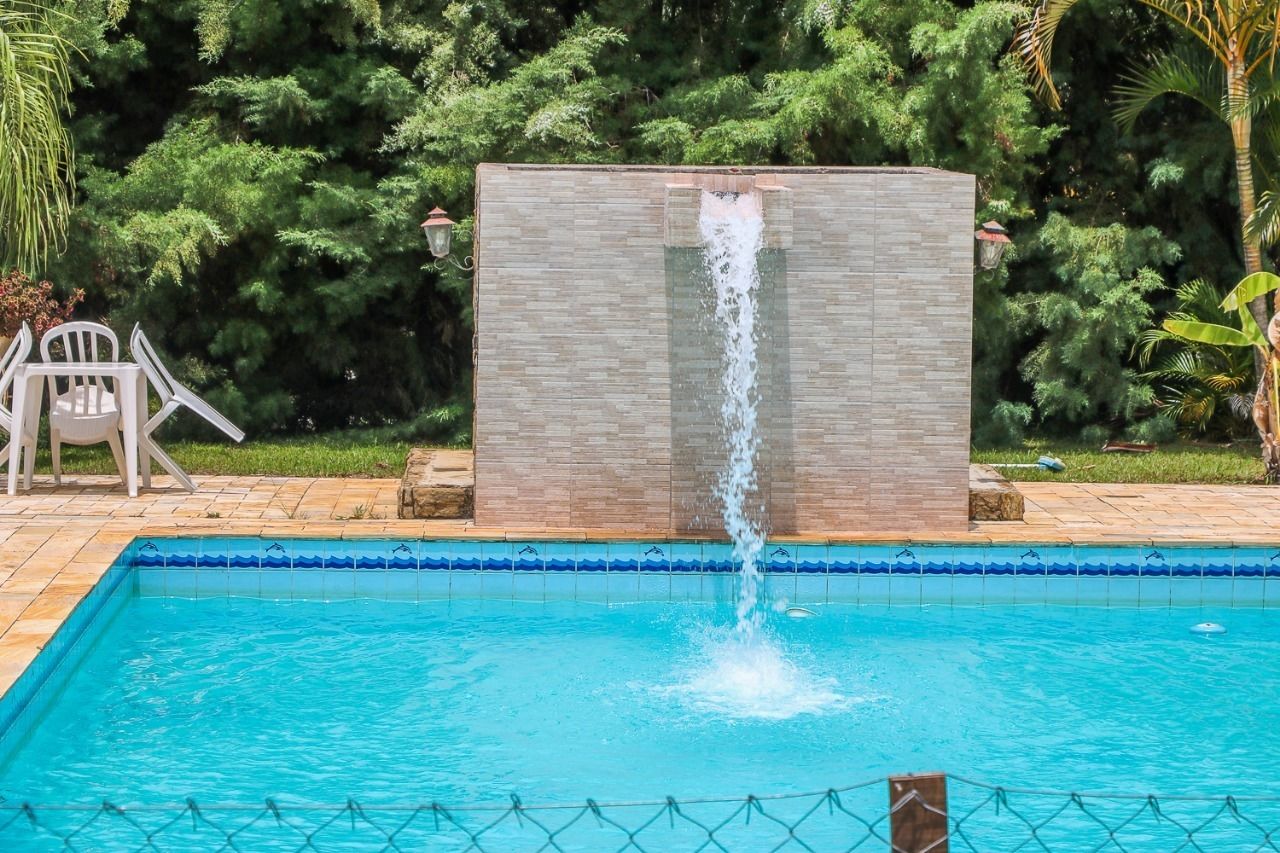 Une piscine agrémentée d’une cascade, entourée de verdure et dotée d’une chaise.