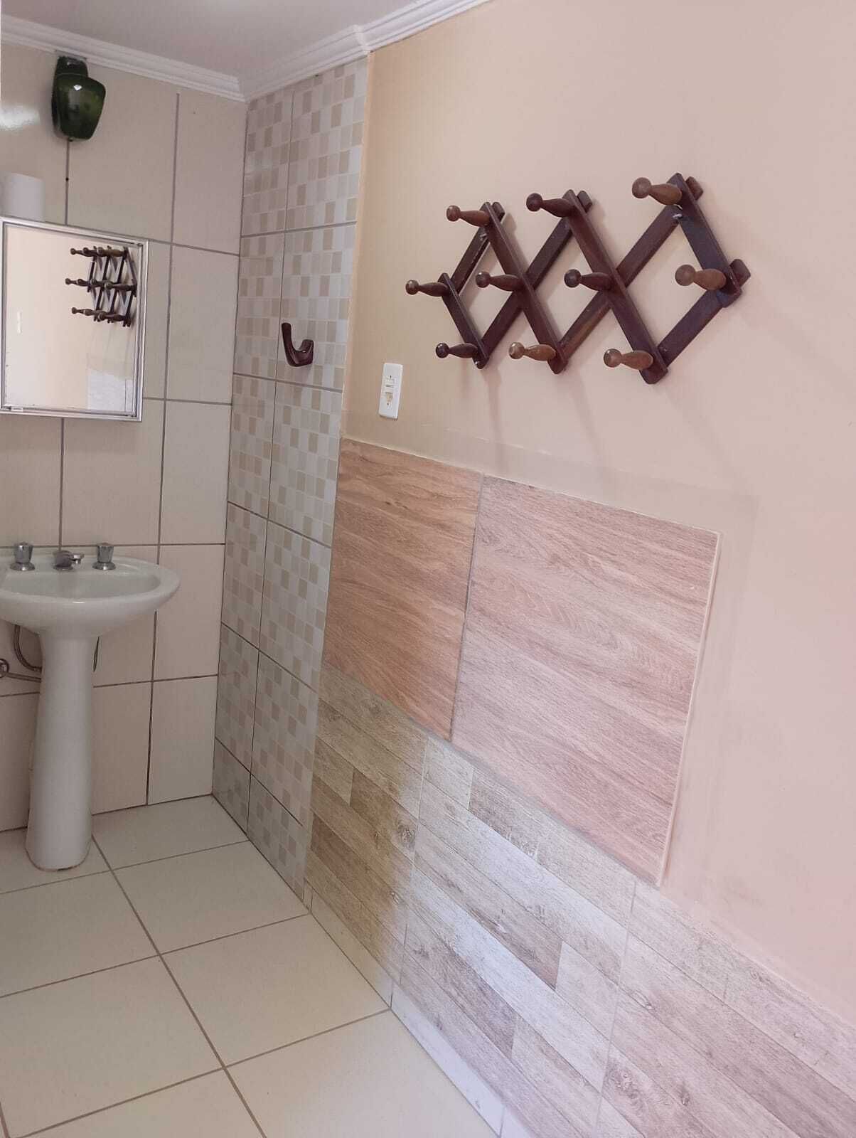 Une salle de bain avec un lavabo, des murs carrelés et un porte-serviettes décoratif en bois.