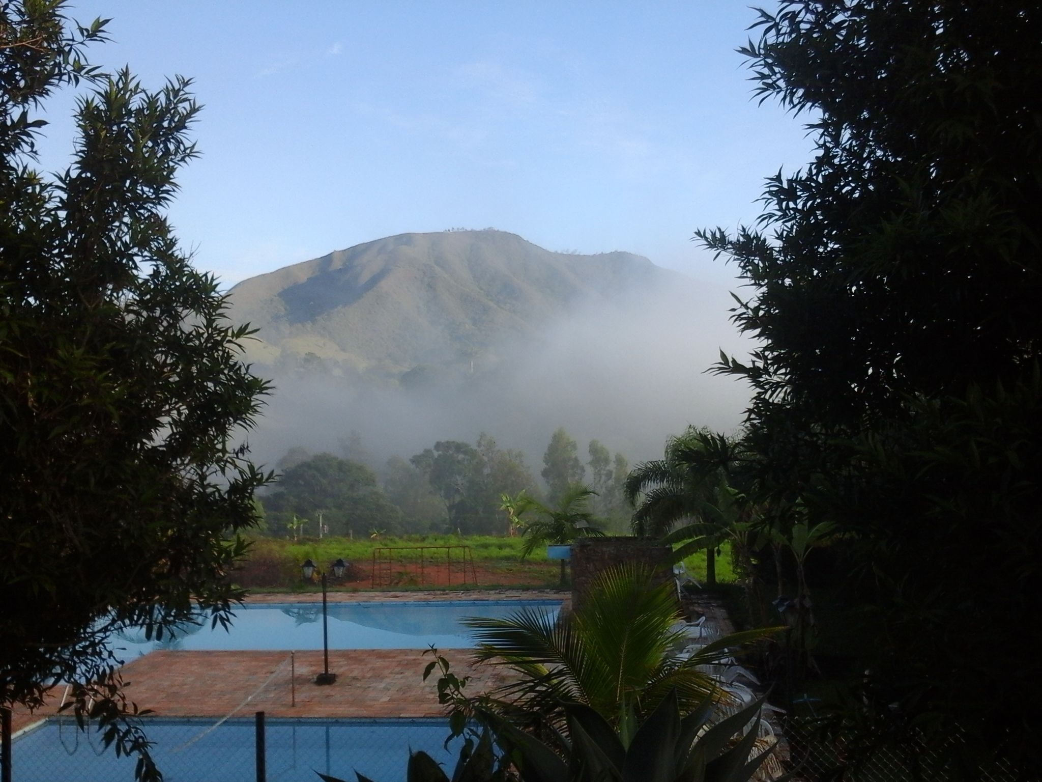 A view of a mountainous landscape with a pool area in the foreground.