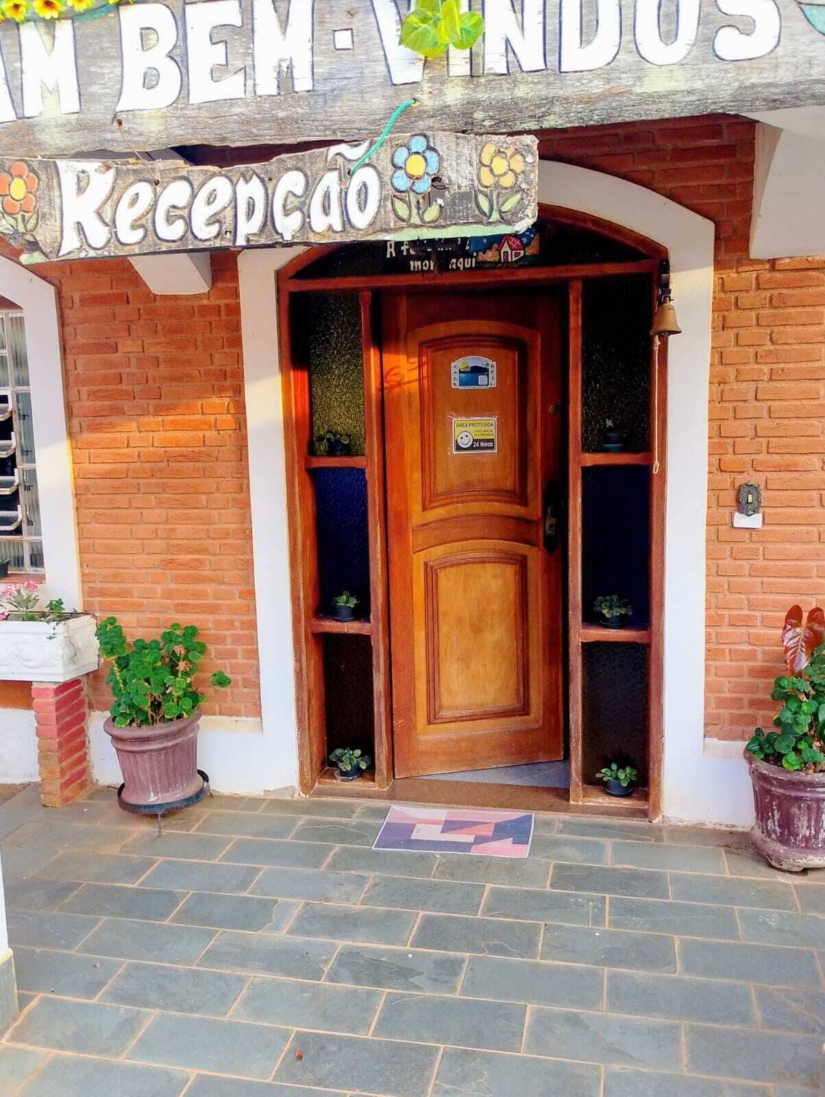 Una zona de recepción con puerta de madera, plantas en macetas y un cartel sobre la puerta.