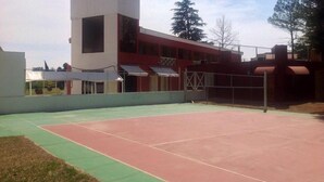 Una cancha deportiva con superficie roja y verde, rodeada de edificios de fachada roja y blanca.