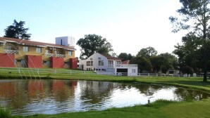 Un edificio con fachada roja y blanca, un pequeño estanque y una valla blanca.