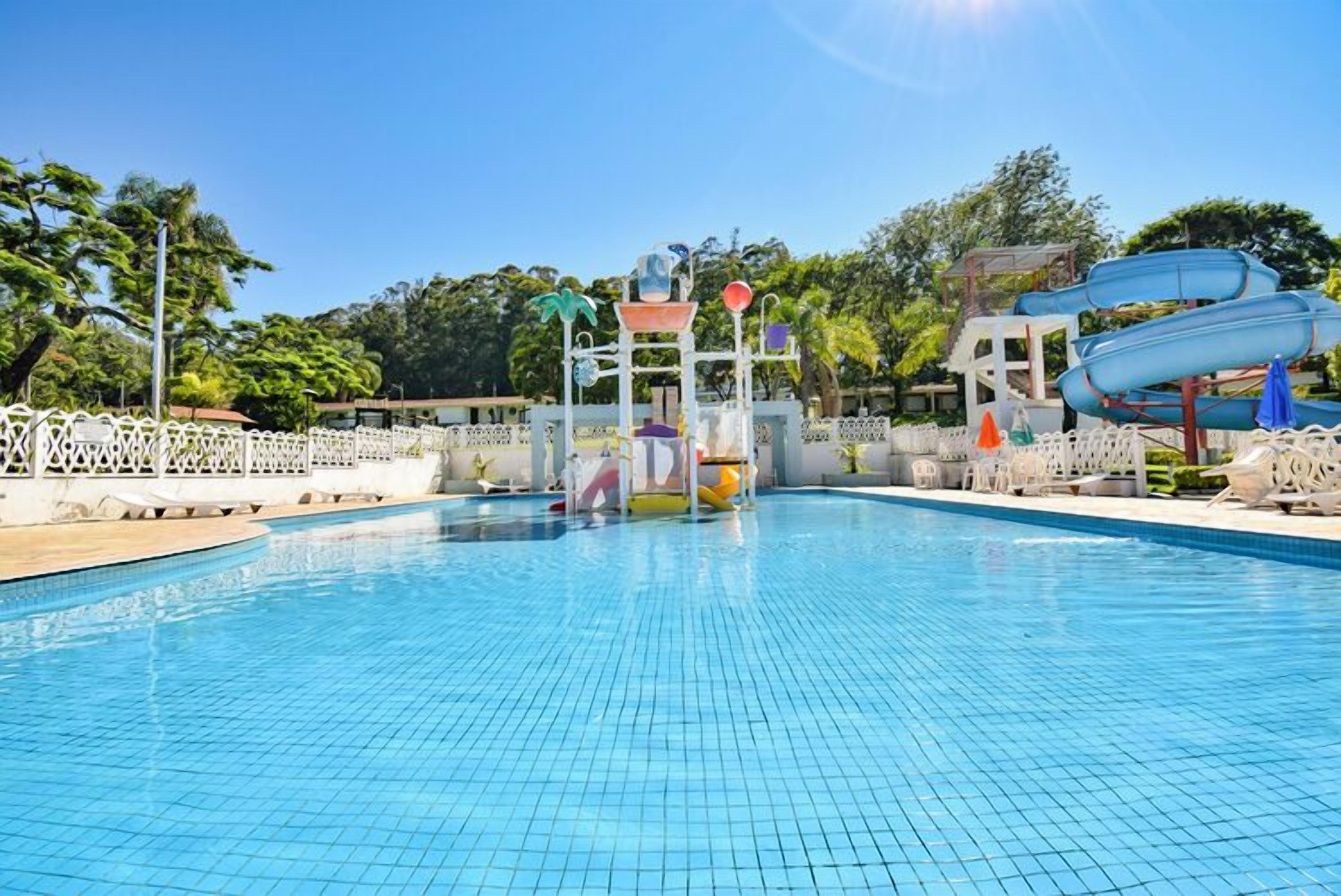 A swimming pool with a water slide and a play structure.