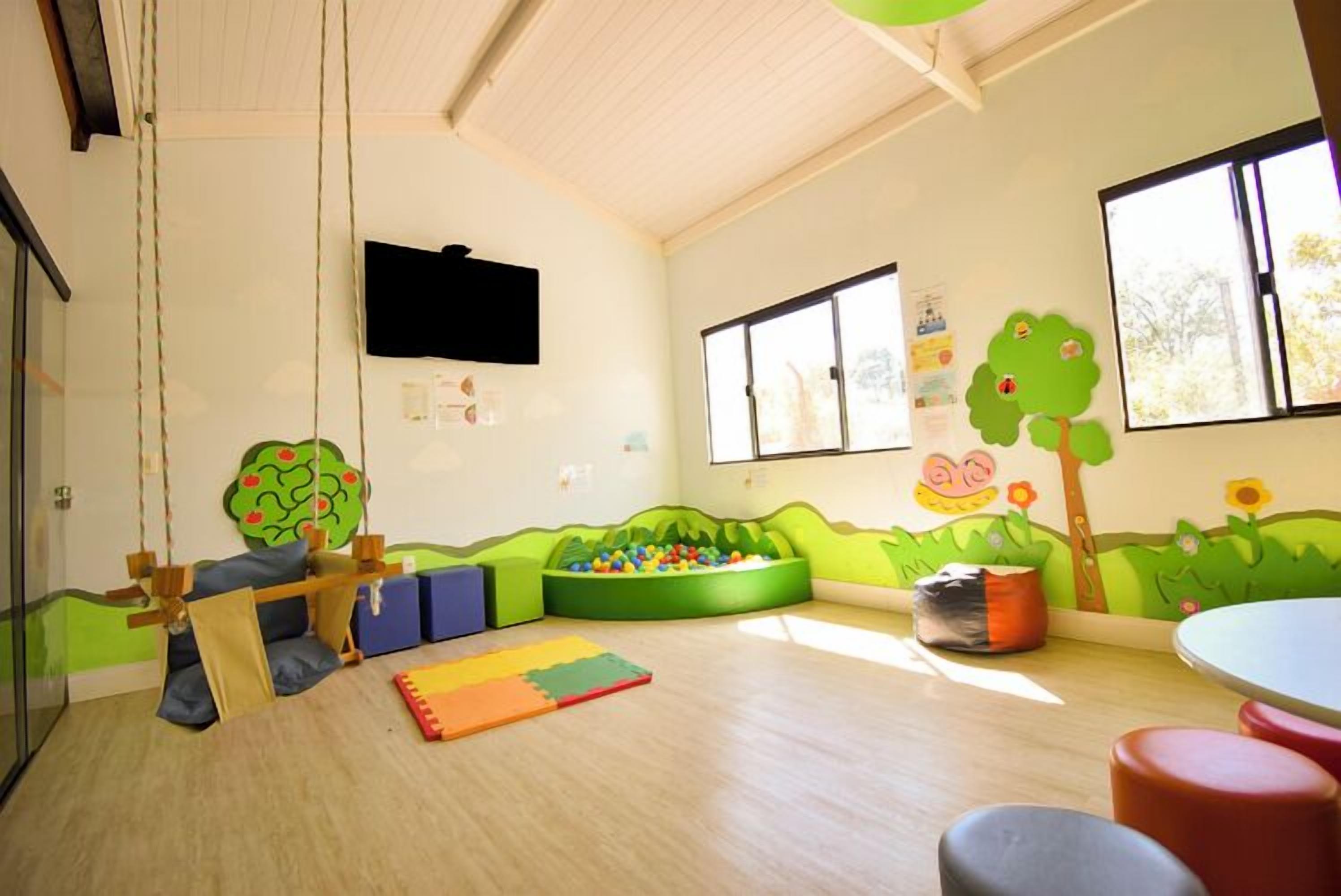 A children's playroom with a swing set, ball pit, and colorful wall decorations.