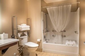 A bathroom with a toilet, a sink, a shower with a curtain, and a bathtub. - Skyline Hotel & Casino (Henderson)