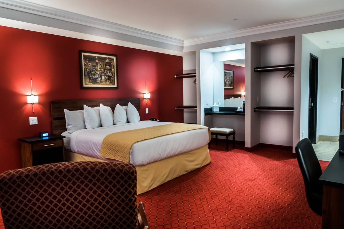 Een hotelkamer met een groot bed, twee nachtkastjes, een bureau, een stoel en een kledingkast.
