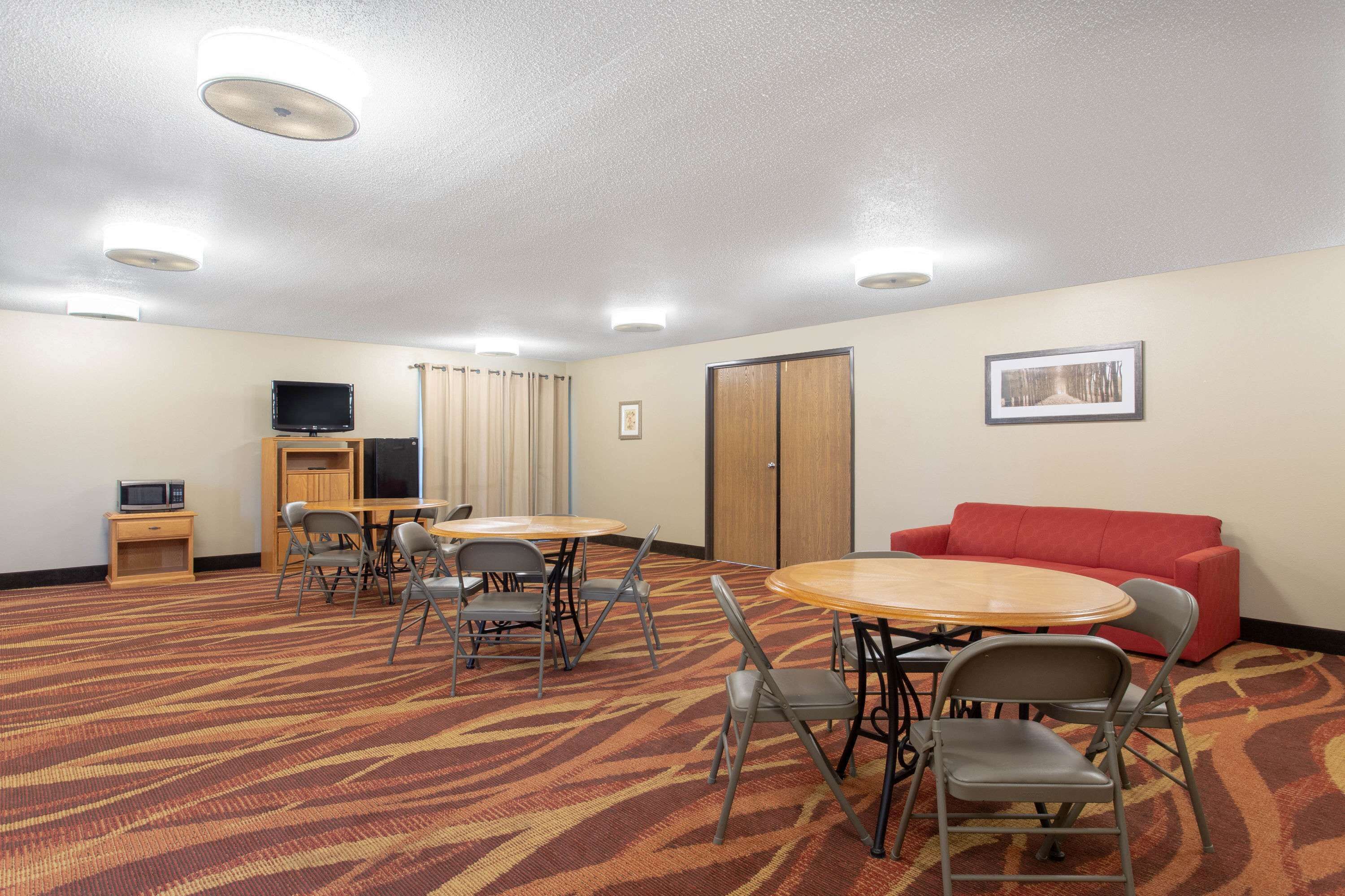 A conference room with a carpeted floor, a red sofa, a television, and a wooden cabinet.