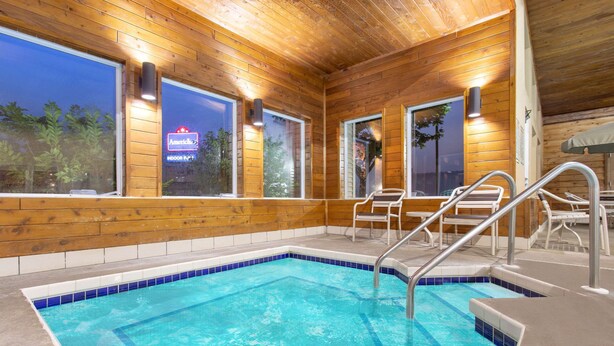 Una cabaña de madera con piscina, ventanas amplias y un patio.