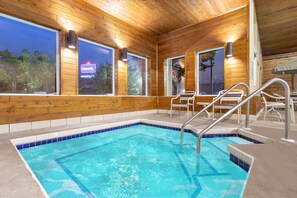A wooden cabin with a swimming pool, large windows, and a patio area.