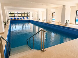 Una piscina cubierta, una piscina al aire libre, tumbonas