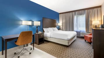 A hotel room with a bed, desk, chair, and two lamps.