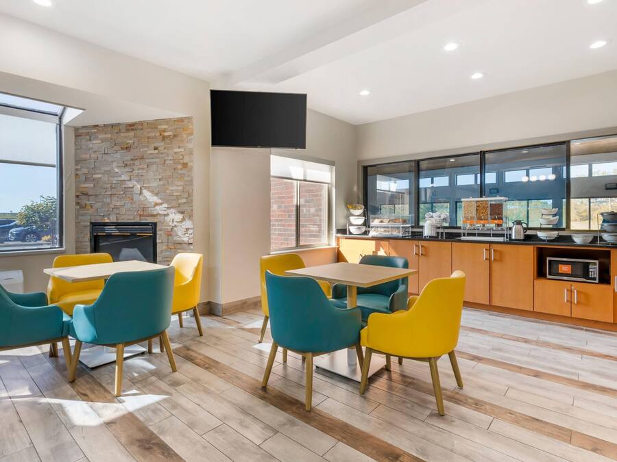 A modern dining area with a stone wall, a flat-screen TV, and a kitchen with wooden cabinets and a microwave.