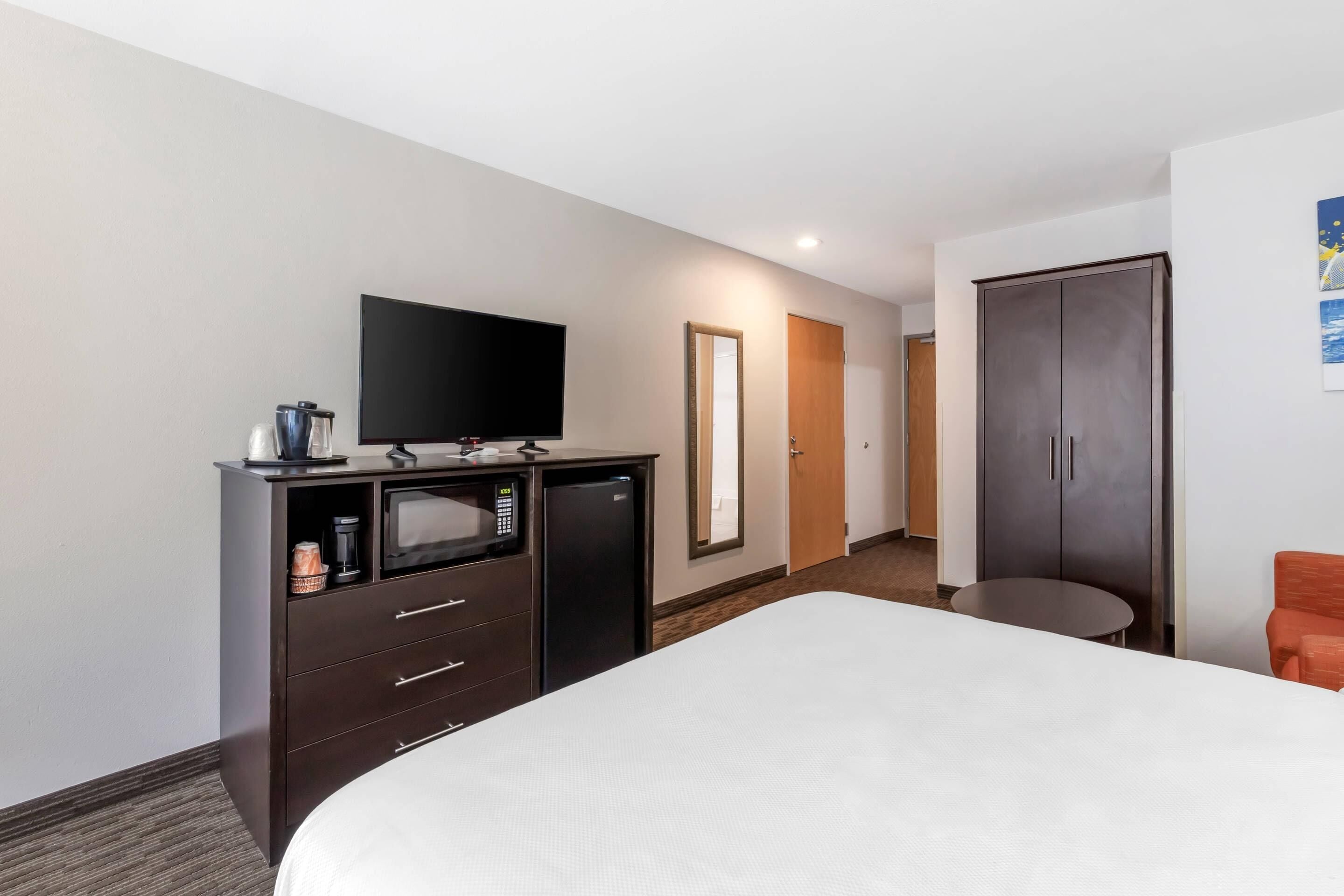 A hotel room with a bed, a TV, a minibar, a desk, and a wardrobe.