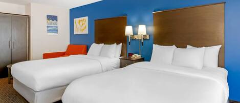 A hotel room with two beds, a nightstand, a phone, and artwork on the wall.