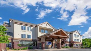 A multi-story hotel with a covered entrance, a sign indicating it is a Comfort Inn, and a parking lot in front.