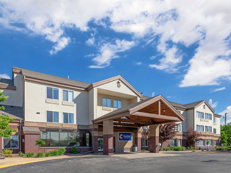 A multi-story hotel with a covered entrance, a sign indicating it is a Comfort Inn, and a parking lot in front.