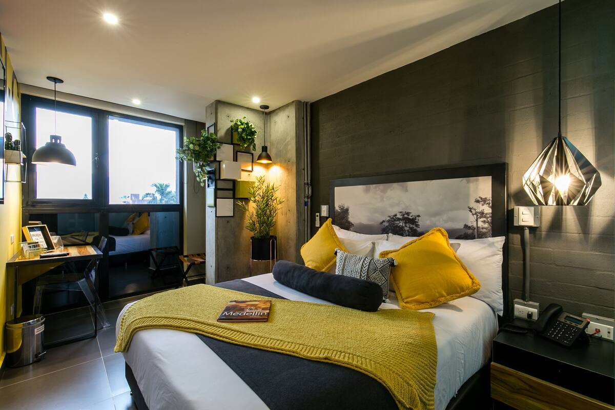 A modern bedroom with a bed, bedside table, and a desk with a chair.