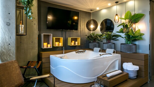 A modern bathroom with a large bathtub, wooden furniture, and potted plants. - Epic Hotel Boutique (Medellín)