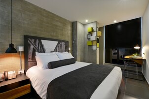 Quarto de hotel moderno com uma cama grande, uma mesa e uma cadeira.